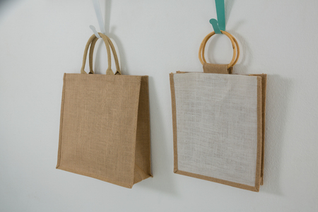 Two bags hanging on hook against white wall