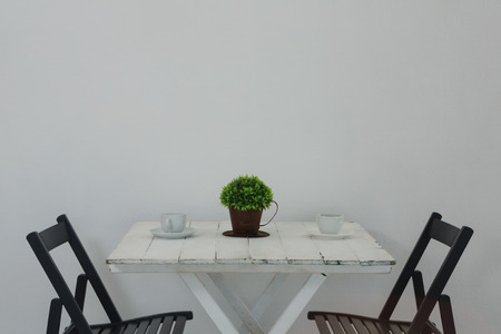 Coffee cup and pot plant on table against wallの写真素材