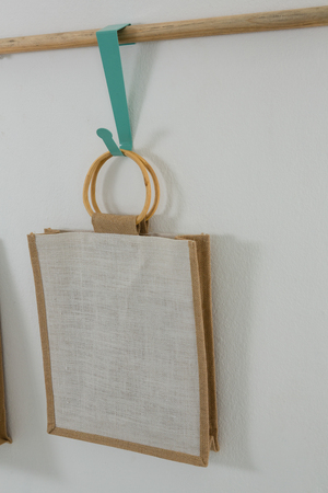 Bag hanging on wooden rod against white wallの写真素材