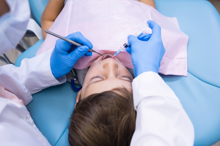 High angle view of dentist holding medical equipment while examining boy at clinicの写真素材