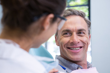 Closeup of happy patient looking at dentist in medical clinicの写真素材