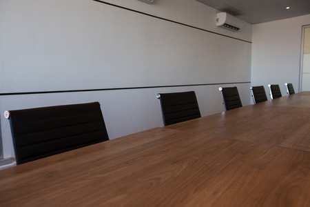 Empty office chairs at conference table in modern meeting roomの写真素材