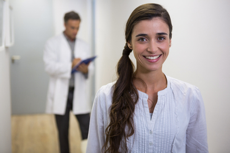 Portrait of smiling woman against dentist standing in lobby at medical clinicの写真素材