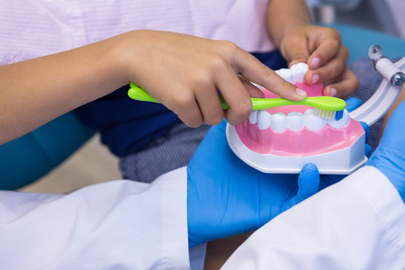 Close-up of dentist and boy brushing dentures at clinicの写真素材