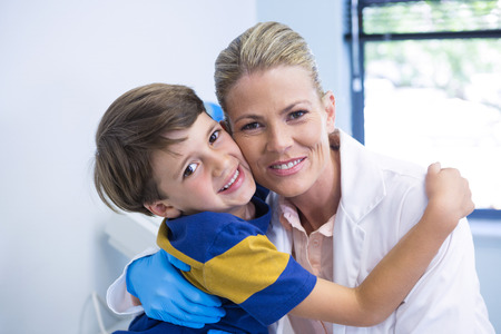 Portrait of smiling dentist with boy at medical clinicの写真素材