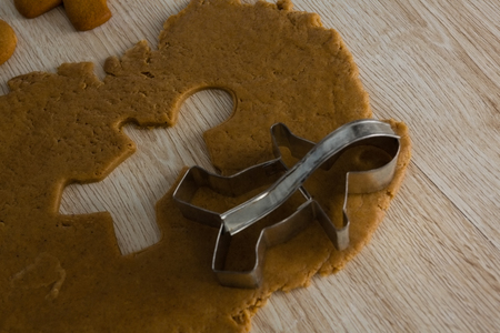 Close-up of gingerbread dough with cookie cutter on wooden tableの写真素材