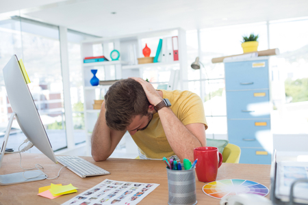 Depressed male executive working on computer in the officeの写真素材
