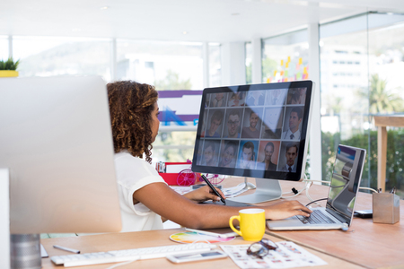 Female executive working over graphic tablet at her desk in officeの写真素材