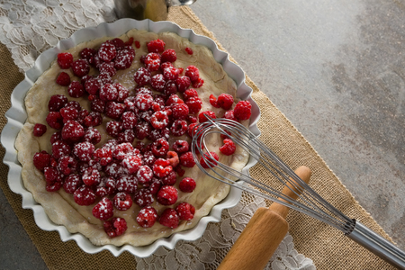 Close-up of red berries on tart with whisker and rolling pin
