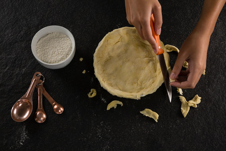 Close-up of woman slicing off extra dough from the moldの写真素材