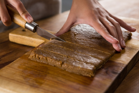 Close-up of woman slicing dough on chopping boardの写真素材