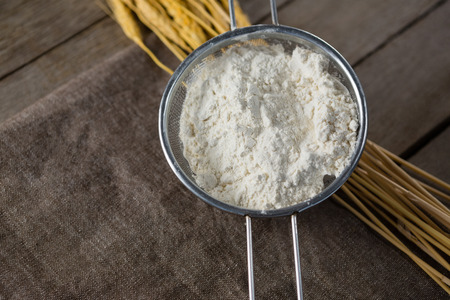 Over head view of flour inside sieve placed over wheat stemの写真素材