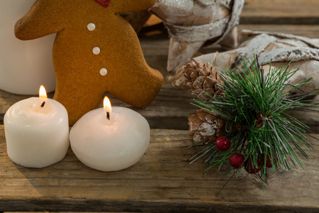 Close up of gingerbread cookie with star shape decorating and illuminated candles on wooden table