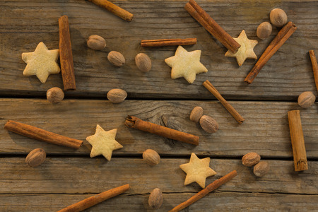Star shape cookies and cinnamon sticks with walnuts on wooden tableの写真素材