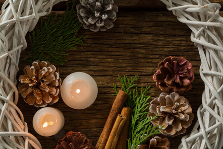 Directly above shot of pine cones with illuminated candles and wreath on wooden tableの写真素材
