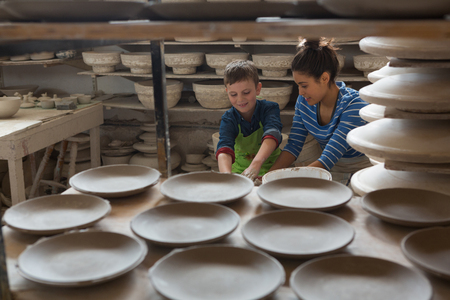 Female potter assisting a boy in pottery workshopの写真素材