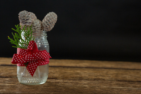 Close up of pine cones in glass jar on wooden table against black backgroundの写真素材