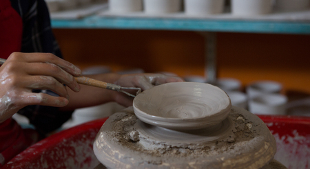 Mid section of female potter molding a bowl with hand toolの写真素材
