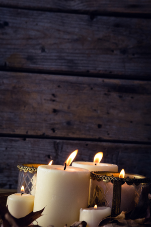 Close-up of lit candles and dry leaves on tableの写真素材
