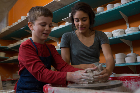 Female potter assisting boy in molding a clay at workshopの写真素材