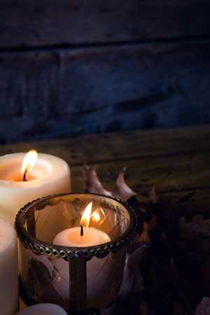 Close-up of lit candles and dry leaves on tableの写真素材