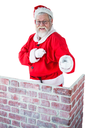 Portrait of santa claus standing behind the chimney and pointing against white backgroundの写真素材