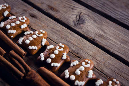 Close-up of gingerbread cookies and cinnamon sticks arranged on wooden plankの写真素材