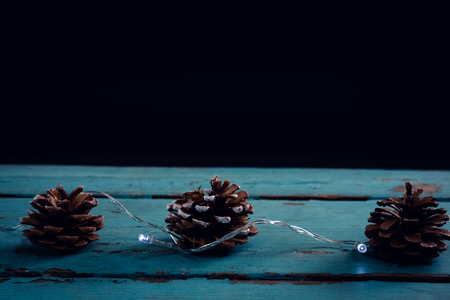 Pine cone decorated with christmas light on wooden plankの写真素材
