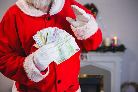 Mid-section of santa claus holding a bundle of eurosの写真素材