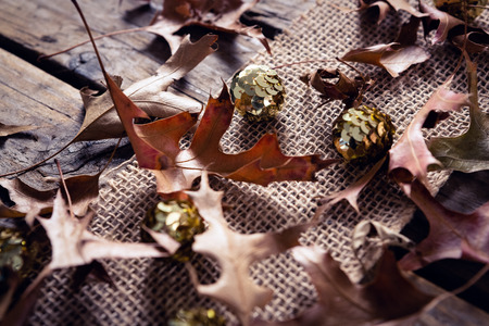 Close-up of sequin balls and dry leaves on wooden plankの写真素材