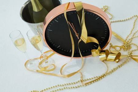 Close-up of champagne with clock and glass on white backgroundの写真素材
