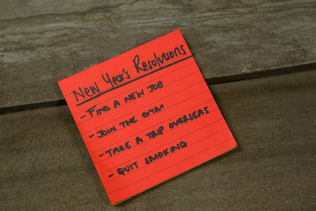 List of new years resolution written on sticky notes on wooden surface