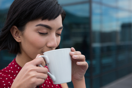 Female executive having coffee in office premisesの写真素材
