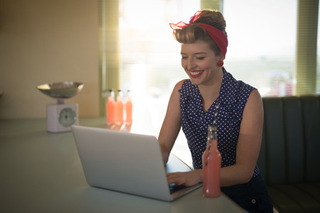 Beautiful woman using laptop while having drink in restaurant