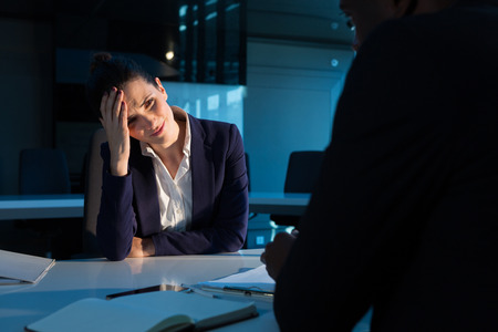 Tensed businesswoman sitting at desk in officeの写真素材