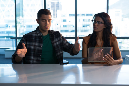 Male and female executive using digital invisible screen in futuristic officeの写真素材