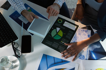Overhead of executives discussing over digital tablet at desk in office