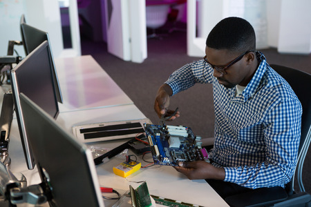 Computer engineer repairing motherboard at desk in office