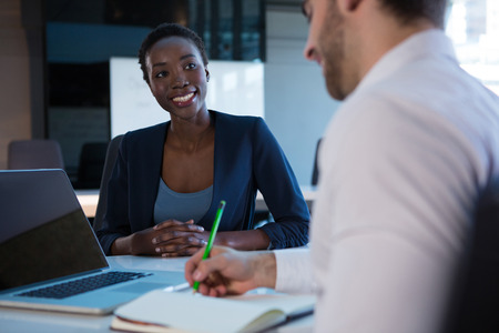 Female executive interacting with her colleague at desk in office