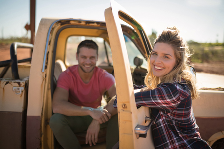 Couple interacting with each other near a car on a sunny dayの写真素材