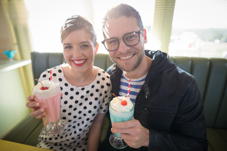 Young couple having milkshake in restaurantの写真素材