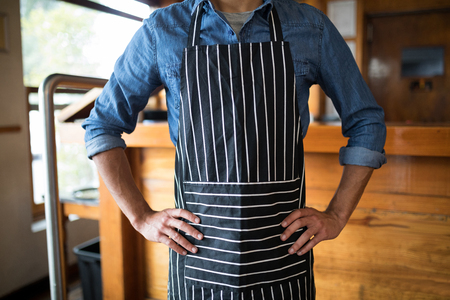 Mid section of waiter standing with hands on hip in barの写真素材
