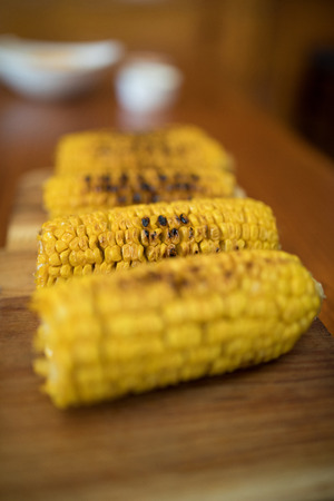 Close-up of baked baby corn on wooden trayの写真素材