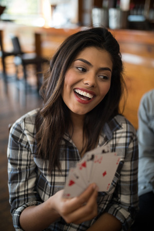 Smiling beautiful woman playing cards in bar