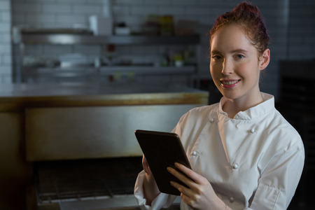 Portrait of female chef using digital tablet in the kitchenの写真素材