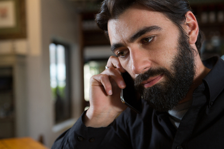 Man talking on mobile phone in barの写真素材