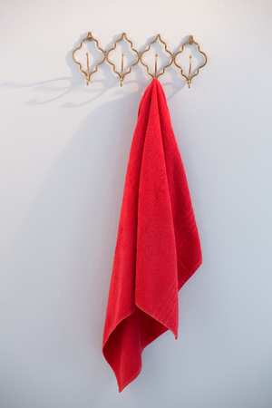 Pink towel hanging on hook against wallの写真素材
