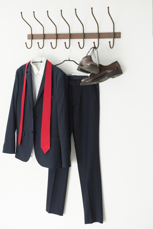 Full suit and shoes hanging on hook against white backgroundの写真素材