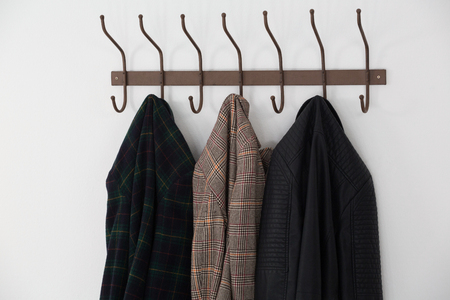 Close-up of warm clothes hanging on hook against white wallの写真素材
