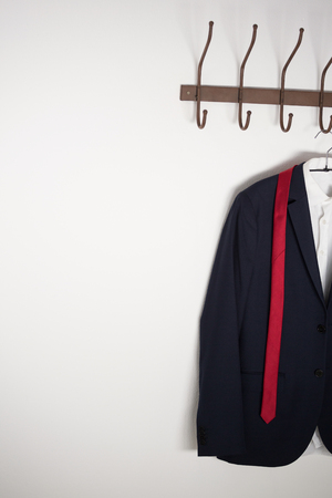 Close-up of blazer hanging on hook against white wallの写真素材